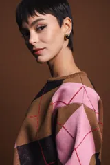 Sweater holgado con diseño de rombos en tonos marrón, negro y rosado, con detalles de lurex en las líneas divisorias. Presenta cuello redondo, mangas largas con puños acanalados y un corte relajado.