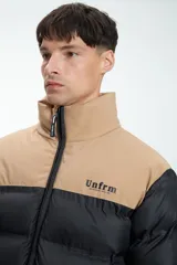 Campera puffer negra y beige con cierre frontal y cuello alto. Estampado con la marca "Unfrm" en el pecho.