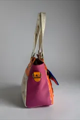 Cartera de cuero de diseño exclusivo con intervención artística de Carolina De Cunto, combinando tonos naranja, azul y detalles en color natu y terra. Cuenta con doble asa de hombro, solapa frontal de pelo sintético azul y herrajes metálicos.