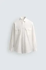 Camisa de corte relajado confeccionada en una mezcla de algodón y seda. Presenta cuello solapa, cierre frontal de botones, mangas largas con puños abotonados y dos bolsillos de plastrón con solapa en el pecho.