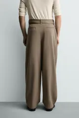 Pantalón de corte balloon fit en color gris, confeccionado en tejido con viscosa. Presenta pliegues frontales, cintura con cinturón integrado a contraste, bolsillos laterales y bolsillos traseros de vivo.