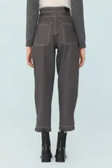 Pantalón gris de corte cropped, con pinzas, costuras a contratono y tablas en los laterales sostenidas con cuatro botones.