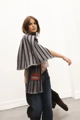 Bufanda tejida gris con rayas verticales negras y parche de paño con bordado.