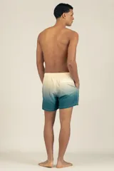 Short de baño con degradé de color beige a azul, con cintura elástica y cordón ajustable. Tiene protección UV50, logo de la marca, dos bolsillos laterales y uno trasero con cierre.