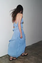 Vestido midi celeste con tirantes finos cruzados en la espalda y volantes en el mismo tejido.