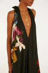 Mono palazzo largo de color negro con estampado de maxi orquídeas coloridas, escote en V pronunciado y tirantes halter que se atan al cuello. Presenta un diseño holgado y fluido.