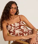 Blusa de breteles finos confeccionada en viscolino con estampado floral en tonos marrones y blancos, escote cuadrado y detalles de pompones en los tirantes.