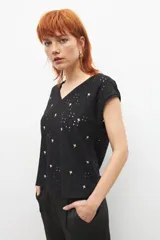 Blusa negra con bordado broderie de flores, escote en V y mangas cortas.