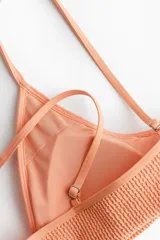 Top de bikini con textura, color salmón, escote en V y tirantes finos ajustables.