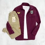 Sobrecamisa bordeaux de gabardina con cuello clásico, cierre frontal abotonado, dos bolsillos con solapa abotonada en el pecho y apliques bordados en el pecho y el hombro. Corte recto y mangas largas con puños abotonados.