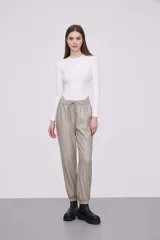Pantalón tipo babucha de eco cuero color cemento, con cintura elástica y cordón de ajuste, bolsillos laterales y puños elásticos en los tobillos.
