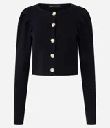 Cardigan de punto negro con cuello redondo, mangas largas abullonadas y cierre frontal con botones decorativos en forma de flor dorada. Presenta un corte corto y ajustado.