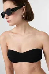 Top de bikini bandeau negro con textura acanalada, tirantes ajustables y removibles.