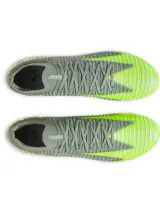 Championes de fútbol Under Armour Shadow Elite 3 FG, diseñados para velocidad y agilidad. Presentan una parte superior de tejido IntelliKnit gris con detalles en verde neón, logotipo de la marca en negro y suela exterior de fibra de carbono para máxima aceleración en superficies naturales.