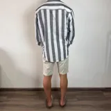 Camisa de manga larga con cuello mao, confeccionada en tejido de lino a rayas verticales en tonos blanco y celeste. Presenta cierre frontal con botones y corte clásico.