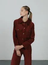 Chaqueta corta negra de pana de algodón con cuello clásico, cierre frontal con botones, dos bolsillos de parche en el pecho y mangas largas.