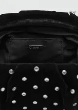 Bolso de mano negro de terciopelo, decorado con pedrería plateada distribuida en toda la superficie y cierre superior.