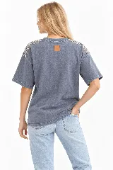 Remera oversize de algodón con acabado stonewash, color gris azulado, manga corta y cuello redondo. Cuenta con apliques bordados a mano en forma de hojas con canutillos plateados sobre los hombros.