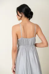 Vestido largo de satén color gris plateado, con breteles finos, escote cruzado y corte debajo del busto.