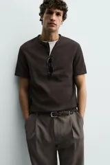 Camiseta de manga corta con cuello panadero y cierre frontal de tres botones. Presenta una textura acanalada y un corte regular fit.