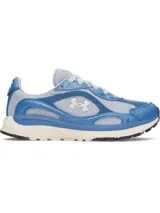 Championes Under Armour modelo UA W Tech Runner, en combinación de celeste y gris, con detalles en azul y suela blanca. Presenta capellada de malla transpirable con superposiciones de cuero y gamuza, entresuela de EVA acolchada y el logotipo de la marca en el lateral.