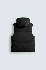 Chaleco regular fit acolchado para hombre, confeccionado en tejido técnico negro con acabado efecto engomado. Cuenta con cuello subido, capucha ajustable, bolsillos de vivo en la cadera, bolsillo interior y bajo ajustable con elástico en los laterales. El cierre frontal es con cremallera.