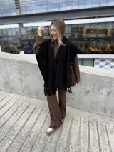 Ruana de tejido de punto en color negro, con diseño abierto y terminación de flecos en el ruedo.