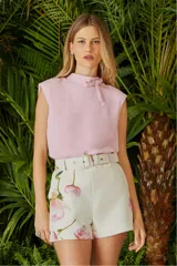 Blusa color rosa pálido sin mangas, con cuello alto y lazo decorativo.