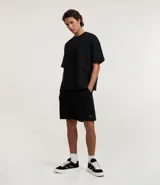 Bermuda masculina de algodón con felpa, color negro, corte slim fit. Presenta cintura elástica con cordón ajustable, bolsillos y etiqueta aplicada.