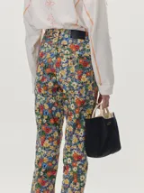 Pantalón de jean de corte recto y tiro medio con estampado floreado multicolor sobre base azul, confeccionado en algodón elastizado.