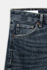 Jeans de tiro medio con corte baggy, cinco bolsillos y bajo con dobladillo. Cierre frontal con cremallera y botón metálico.