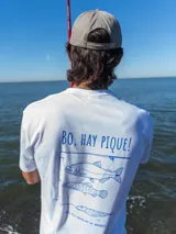 Remera blanca de manga corta con estampa en la espalda en color azul que incluye la frase 'Bo, hay pique!' y dibujos de peces y una caña de pescar.