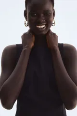 Vestido corto negro de sarga, sin mangas, con escote cuadrado y cierre oculto en la espalda. Presenta costuras princesa en el frente y la espalda para un ajuste entallado.