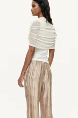 Pantalón wide leg de tejido plisado con ligero brillo, color beige, con cintura elástica y bolsillos laterales.