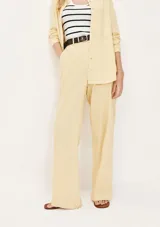 Pantalón de vestir color beige claro, de tiro alto y corte recto ancho, con pinzas frontales y cierre oculto.