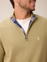 Sweater de punto color gris, con cuello alto y cierre frontal parcial con detalle de tela a cuadros en el interior. Presenta puños y ruedo acanalados y logo bordado en el pecho.
