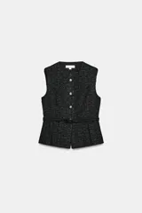 Chaleco de tejido tipo tweed en color negro, con cuello redondo y cierre frontal de botones dorados. Presenta un diseño entallado con cinturón integrado del mismo tejido y bajo con pliegues.