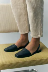 Zapato destalonado de cuero color negro, con punta cuadrada y diseño minimalista.