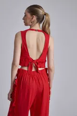 Conjunto de dos piezas color rojo, compuesto por un top sin mangas con detalle de volado fruncido en el bajo y un pantalón ancho de tiro alto con volados largos a lo largo de las costuras laterales exteriores.