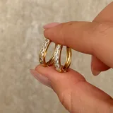 Aros tipo argolla pequeña en color dorado, con incrustaciones de piedras brillantes en la parte frontal.
