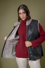 Chaleco reversible de cuero negro con interior de piel sintética gris. Presenta cierre frontal completo y bolsillos laterales con cierre.