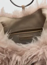 Bolso de mano con diseño triangular y textura de pelo sintético en color beige. Cuenta con un detalle de aro metálico circular en la parte frontal y asa integrada para llevar al hombro.
