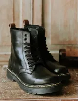 Bota negra de cuero charol con cordones, suela track color caramelo y tirador trasero.