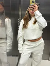 Conjunto deportivo compuesto por un buzo tipo hoodie cropped de corte holgado y un pantalón wide leg con cintura elástica. Ambas prendas están confeccionadas en algodón de alto gramaje en color crudo.