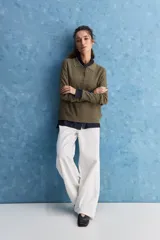 Sweater de punto color verde militar, con cuello polo y cierre frontal de botones, de manga larga con puños elastizados y diseño texturizado con relieve geométrico.