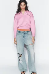 Sweater tipo polo de punto liso, con cuello solapa, manga larga y bolsillo delantero de plastrón. Presenta cierre frontal con botones y puños y ruedo acanalados.