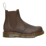 Botas Chelsea Dr. Martens modelo 2976, confeccionadas en cuero Crazy Horse color marrón con acabado envejecido. Presentan paneles elásticos laterales, suela de goma con costuras amarillas características y tirador trasero.