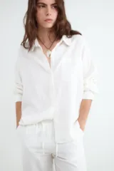 Camisa de manga larga color negro, de corte holgado, cuello camisero, cierre frontal con botones y un bolsillo aplicado en el pecho. Confeccionada en mezcla de lino y viscosa.