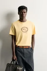 Camiseta regular fit de color amarillo, de cuello redondo y manga corta, con estampa frontal en contraste de un rancho y la inscripción "Rancho Lane Worn Heritage".