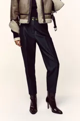 Pantalón de tiro alto y corte tobillero, confeccionado en tejido de aspecto denim oscuro. Presenta diseño de pinzas frontales, bolsillos laterales y cierre frontal con cremallera, botón y gancho. Incluye un cinturón fino a tono con hebilla metálica dorada.